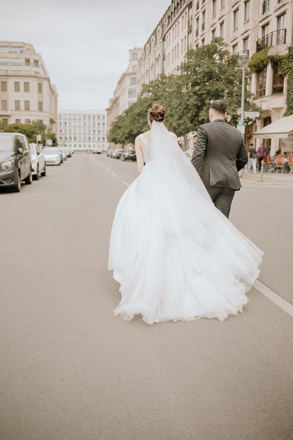 Ein etwas anderes Foto von einem Brautpaar. Alev und Cenk laufen auf der Straße. Das Foto ist Bestandteil eines Brautpaarshootings in Berlin am Konzerthaus.