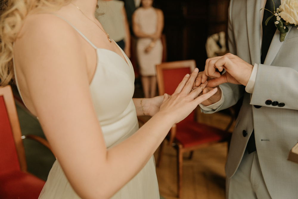 Der Bräutigam steckt seiner Braut gerade den Ring an. Standesamt Neukölln. Hochzeitsreportage.