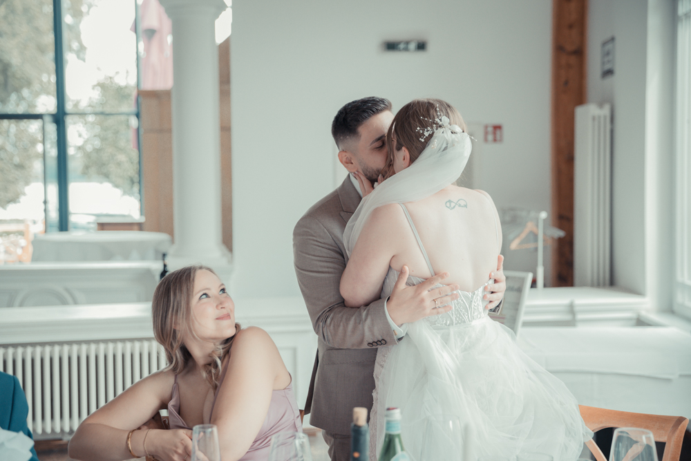 Das Brautpaar küsst sich und die Trauzeugin guckt das Brautpaar an. Das Brautpaar bekommt gar nicht mit, dass es fotografiert wird und somit kann ich diesem wunderschönen Moment authentisch festhalten.