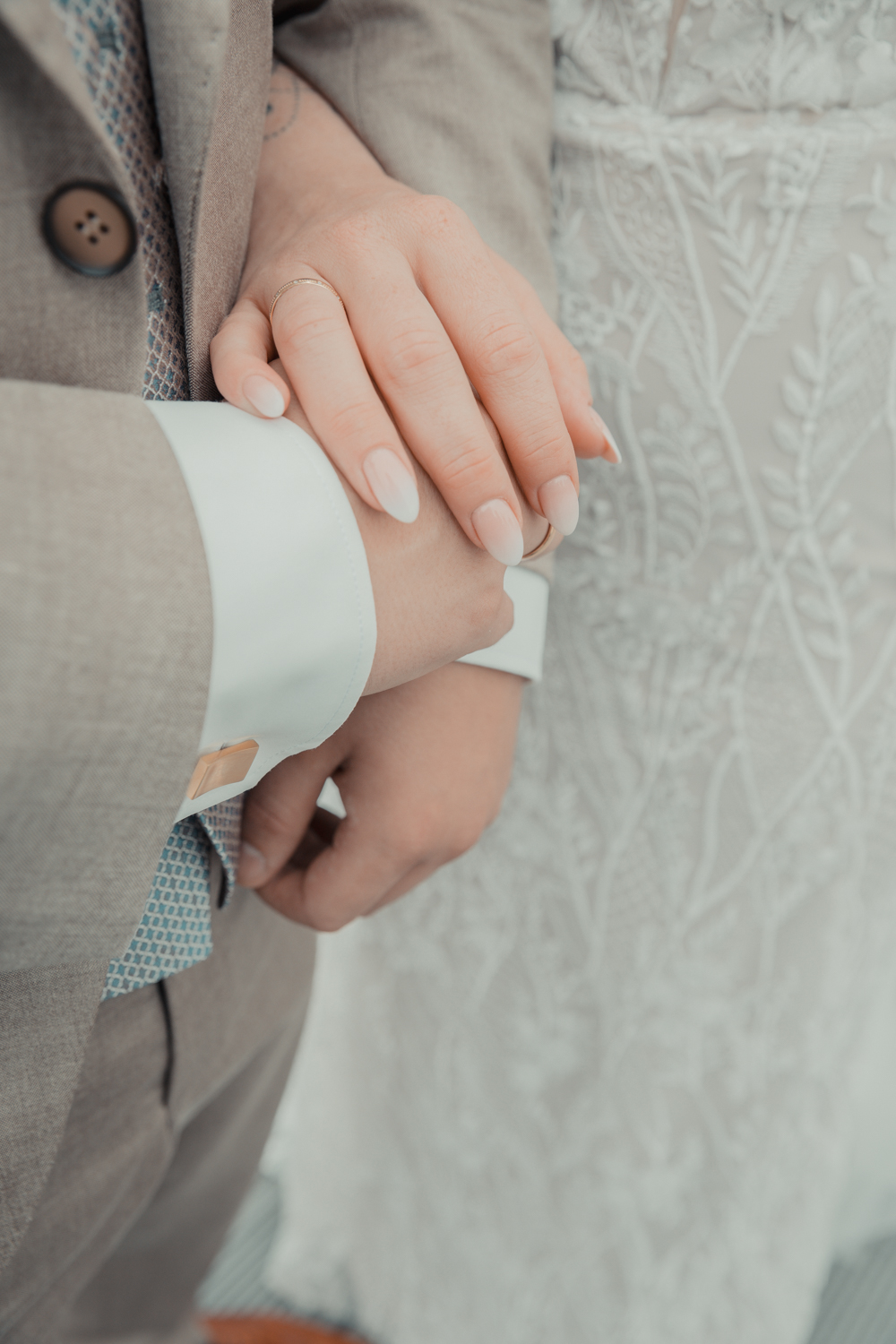 Detailshooting am Grunewaldturm vom Brautpaar. Auf dem Foto sieht man die Hände des Brautpaars , sowie die goldenen manschettenknöpfe des Bräutigams. Teil einer ganztägigen Hochzeitsreportage.